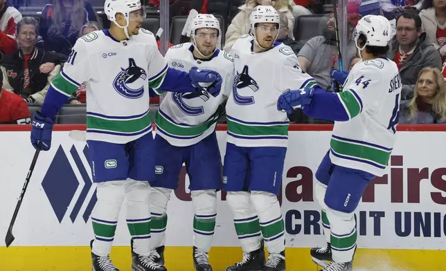 Vancouver Canucks center Pius Suter, second from right, celebrates after his goal against the Detroit Red Wings with center Dakota Joshua (81), defenseman Erik Brannstrom (26) and left wing Kiefer Sherwood (44) during the second period of an NHL hockey game Sunday, Dec. 1, 2024, in Detroit. (AP Photo/Duane Burleson)