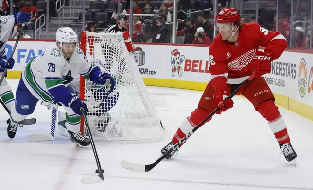 Vancouver Canucks defenseman Erik Brannstrom (26) can't stop a pass by Detroit Red Wings right wing Christian Fischer (36) during the first period of an NHL hockey game Sunday, Dec. 1, 2024, in Detroit. (AP Photo/Duane Burleson)