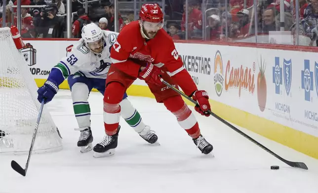 Vancouver Canucks center Teddy Blueger (53) puts the pressure on Detroit Red Wings center Michael Rasmussen (27) during the first period of an NHL hockey game Sunday, Dec. 1, 2024, in Detroit. (AP Photo/Duane Burleson)