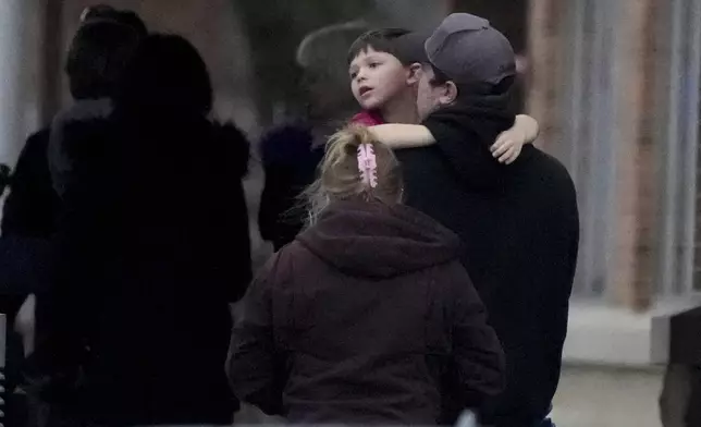 A child is embraced at the SSMI Health Center, set up as a reunification center, following a shooting, Monday, Dec. 16, 2024 in Madison, Wis. (AP Photo/Morry Gash)