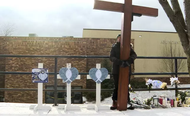 Dan Beazley stands with the homemade cross he brought from Michigan for victims of a shooting at Abundant Life Christian School Wednesday, Dec. 18, 2024, in Madison, Wis. (AP Photo/Mark Vancleave)