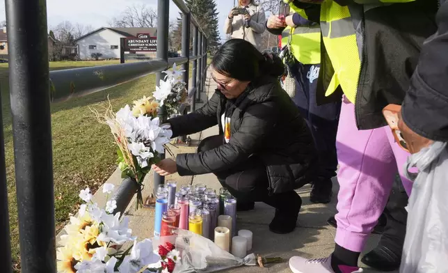 A resident places some flowers outside the Abundant Life Christian School Tuesday, Dec. 17, 2024 in Madison, Wis., following a shooting on Monday. (AP Photo/Morry Gash)