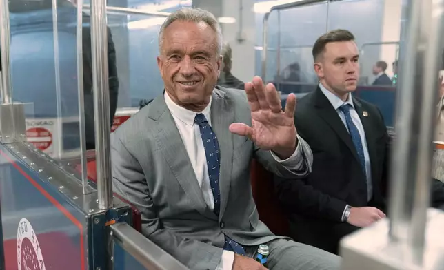 Robert F. Kennedy Jr., President-elect Donald Trump's nominee to be Secretary of Health and Human Services, waves to the media as he rides the train to go to meet with Sen. John Thune, R-S.D. at the Capitol in Washington, Tuesday, Dec. 17, 2024. (AP Photo/Jose Luis Magana)