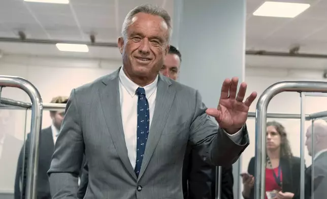 Robert F. Kennedy Jr., President-elect Donald Trump's nominee to be Secretary of Health and Human Services, waves to the media as he rides the train to go to meet with Sen. John Thune, R-S.D. at the Capitol in Washington, Tuesday, Dec. 17, 2024. (AP Photo/Jose Luis Magana)