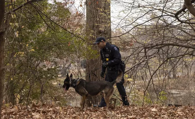 An NYPD police officer and K-9 dog search around a lake in Central Park, Monday, Dec. 9, 2024, in New York. (AP Photo/Yuki Iwamura)