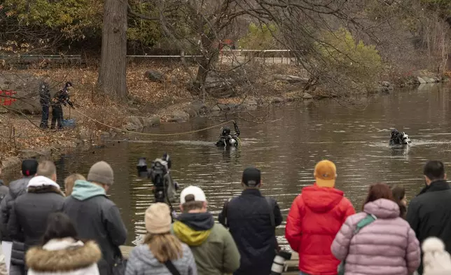 People watch the NYPD officers in diving suits search the lake in the Central Park, Monday, Dec. 9, 2024, in New York. (AP Photo/Yuki Iwamura)