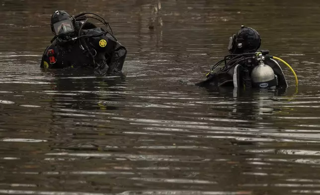 NYPD officers in diving suits search a lake in Central Park, Monday, Dec. 9, 2024, in New York. (AP Photo/Yuki Iwamura)