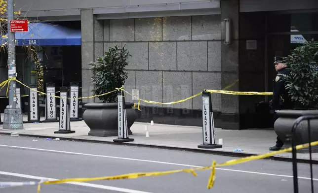 A New York police officer stands outside the Hilton Hotel in midtown Manhattan where Brian Thompson, the CEO of UnitedHealthcare, was fatally shot, Wednesday, Dec. 4, 2024, in New York. (AP Photo/Stefan Jeremiah)