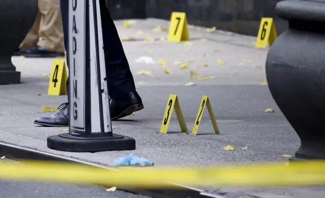 Members of the New York police crime scene unit investigate bullets lying on the sidewalk at the scene outside the Hilton Hotel in midtown Manhattan where Brian Thompson, the CEO of UnitedHealthcare, was fatally shot, Wednesday, Dec. 4, 2024, in New York. (AP Photo/Stefan Jeremiah)