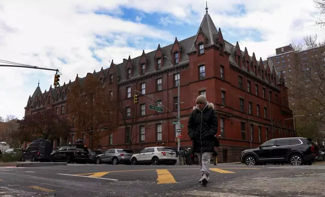 A woman crosses Amsterdam Avenue outside the HI New York City hostel, Thursday, Dec. 5, 2024, in New York, where police say the suspect in the killing of UnitedHealthcare CEO Brian Thompson may have stayed.(AP Photo/Yuki Iwamura)