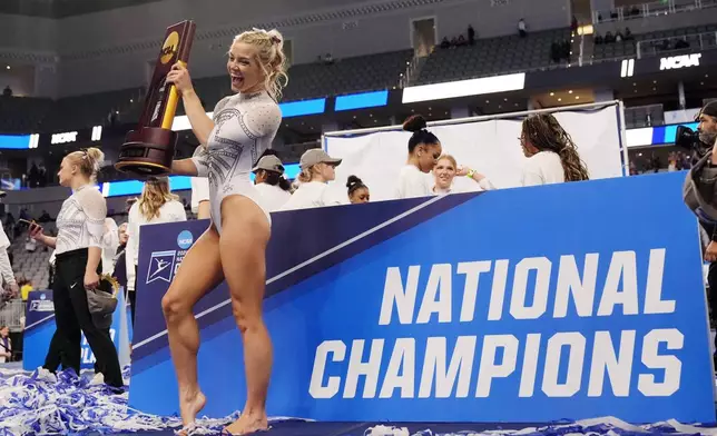 FILE - LSU's Olivia Dunne poses for a photo holding the trophy following the team's win in the NCAA women's gymnastics championships in Fort Worth, Texas, Saturday, April 20, 2024. (AP Photo/Tony Gutierrez, File)