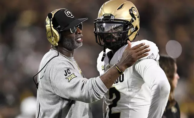 FILE - Colorado head coach Deion Sanders, left, talks with quarterback Shedeur Sanders (2) during a timeout in the second half of an NCAA college football game against Central Florida, Saturday, Sept. 28, 2024, in Orlando, Fla. (AP Photo/Phelan M. Ebenhack, File)