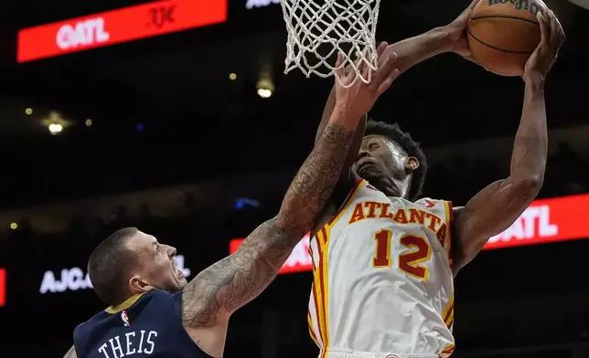 Atlanta Hawks forward De'Andre Hunter (12) grabs a rebound from New Orleans Pelicans center Daniel Theis (10) during the first half of an NBA basketball game, Monday, Dec. 2, 2024, in Atlanta. (AP Photo/Mike Stewart)