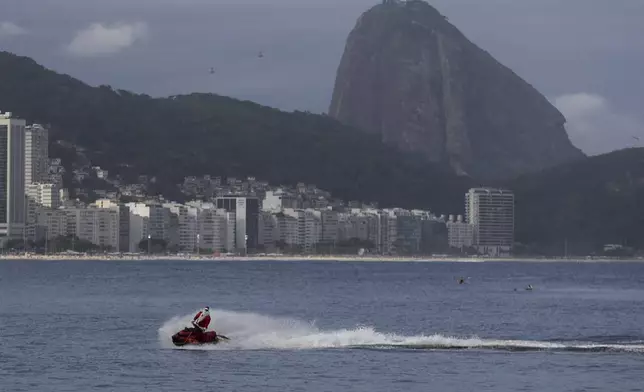 A firefighter dressed as Santa Claus drives a Jet Ski by Copacabana Beach in Rio de Janeiro, Tuesday, Dec. 17, 2024. (AP Photo/Bruna Prado)