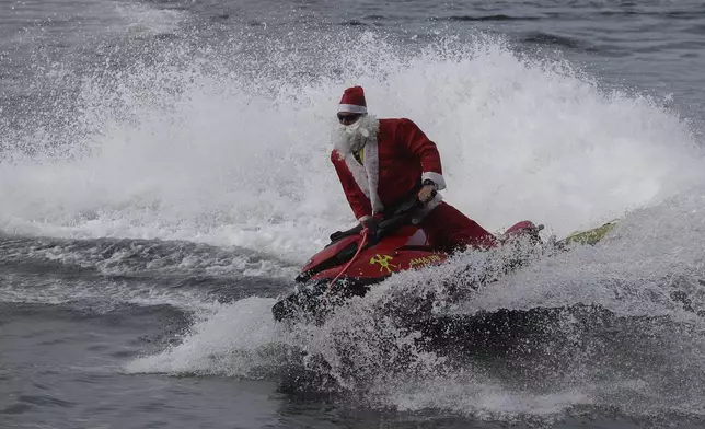 A firefighter dressed as Santa Claus drives a Jet Ski by Copacabana Beach in Rio de Janeiro, Tuesday, Dec. 17, 2024. (AP Photo/Bruna Prado)