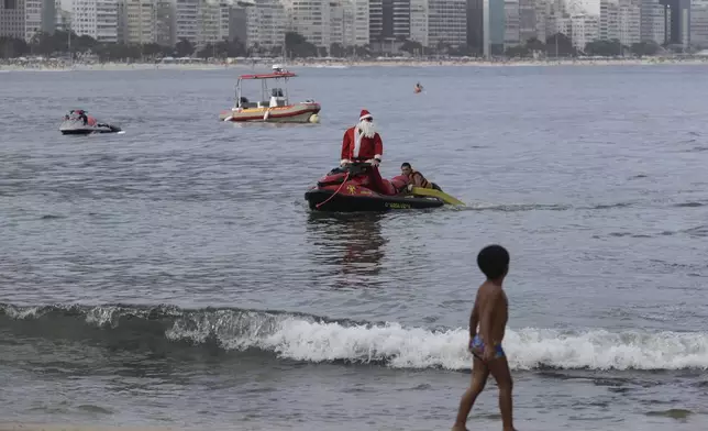 A firefighter dressed as Santa Claus rescues a man on Copacabana Beach in Rio de Janeiro, Tuesday, Dec. 17, 2024. (AP Photo/Bruna Prado)