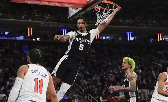 San Antonio Spurs' Stephon Castle, top, reacts after dunking the ball during the first half of an NBA basketball game against the New York Knicks, Wednesday, Dec. 25, 2024, in New York. (AP Photo/Seth Wenig)