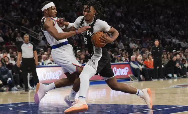 San Antonio Spurs' Stephon Castle, right, drives to the basket past New York Knicks' Miles McBride during the first half of an NBA basketball game, Wednesday, Dec. 25, 2024, in New York. (AP Photo/Seth Wenig)