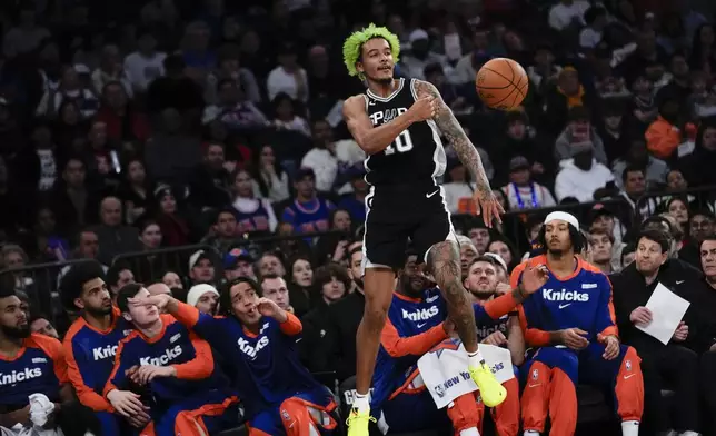 San Antonio Spurs' Jeremy Sochan throws the ball back in-bounds as he falls into the New York Knicks bench during the first half of an NBA basketball game, Wednesday, Dec. 25, 2024, in New York. (AP Photo/Seth Wenig)