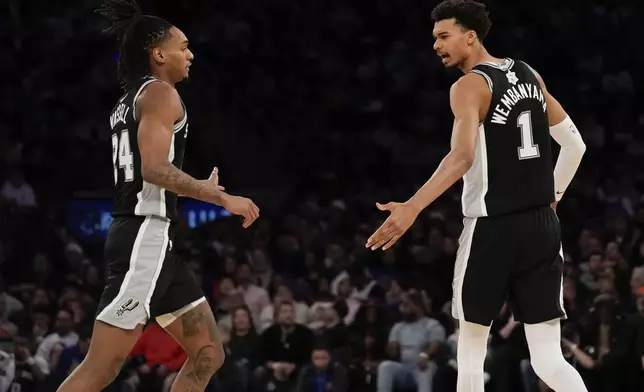 San Antonio Spurs' Victor Wembanyama, right, and Devin Vassell react during the first half of an NBA basketball game against the New York Knicks, Wednesday, Dec. 25, 2024, in New York. (AP Photo/Seth Wenig)