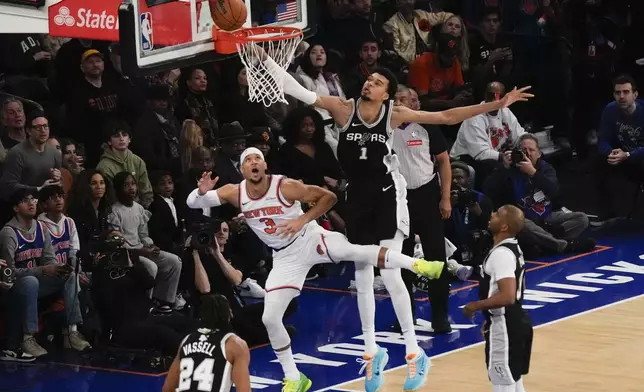 San Antonio Spurs' Victor Wembanyama (1), top right, commits goaltending on a shot put up by New York Knicks' Josh Hart (3), top left, during the first half of an NBA basketball game, Wednesday, Dec. 25, 2024, in New York. (AP Photo/Seth Wenig)