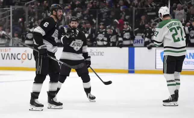 Los Angeles Kings defenseman Joel Edmundson, left, is congratulated by defenseman Kyle Burroughs, center, after scoring as Dallas Stars left wing Mason Marchment skates away during the second period of an NHL hockey game, Wednesday, Dec. 4, 2024, in Los Angeles. (AP Photo/Mark J. Terrill)