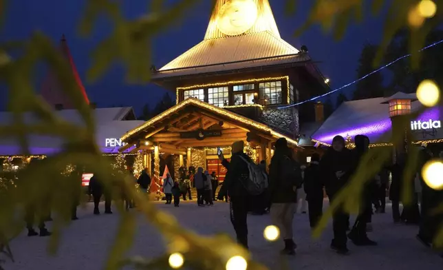 Tourists gather at Santa Claus Village, a winter-themed amusement park perched on the edge of the Arctic Circle, in Rovaniemi, Finland, Wednesday, Dec. 4, 2024. (AP Photo/James Brooks)