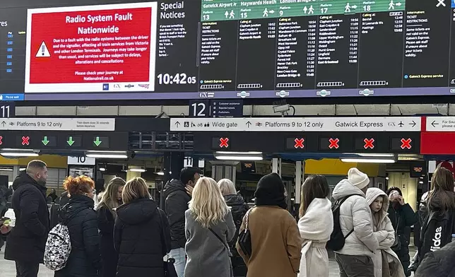 Travellers look at the information board at Victoria Station in London, Friday, Dec. 6, 2024 as rail travellers across Britain are facing disruption after a fault in a radio system used by drivers and signalers nationwide prompted cancellations across the network.(AP Photo/Kirsty Wigglesworth)