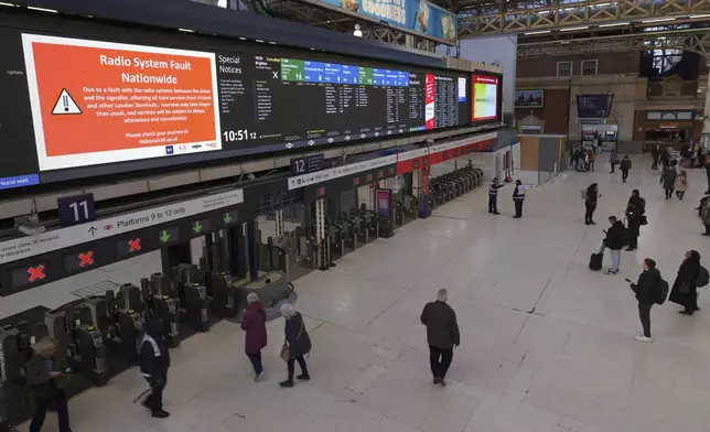 Travellers look at the information board at Victoria Station in London, Friday, Dec. 6, 2024 as rail travellers across Britain are facing disruption after a fault in a radio system used by drivers and signalers nationwide prompted cancellations across the network.(AP Photo/Kirsty Wigglesworth)