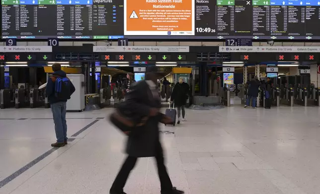 Travellers look at the information board at Victoria Station in London, Friday, Dec. 6, 2024 as rail travellers across Britain are facing disruption after a fault in a radio system used by drivers and signalers nationwide prompted cancellations across the network.(AP Photo/Kirsty Wigglesworth)