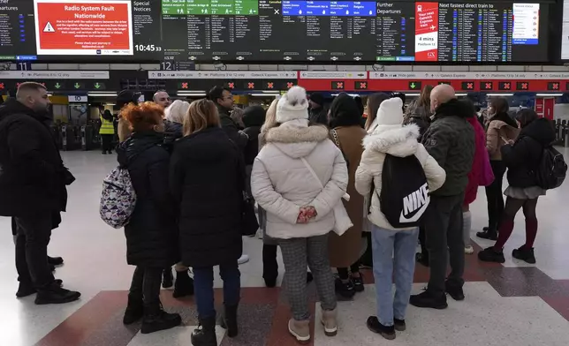Travellers look at the information board at Victoria Station in London, Friday, Dec. 6, 2024 as rail travellers across Britain are facing disruption after a fault in a radio system used by drivers and signalers nationwide prompted cancellations across the network.(AP Photo/Kirsty Wigglesworth)