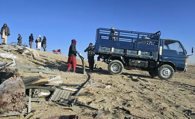 People clear debris from damaged buses following an accident in Ghazni province, southeastern Afghanistan, Thursday, Dec. 19, 2024. (AP Photo/Gulabuddin Amiri)