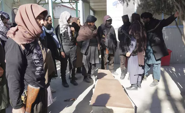 Afghan Taliban fighters stand near the body of a victim of a bus accident, at a hospital in Ghazni province, southeastern Afghanistan, on Thursday, Dec. 19, 2024. (AP Photo/Gulabuddin Amiri)