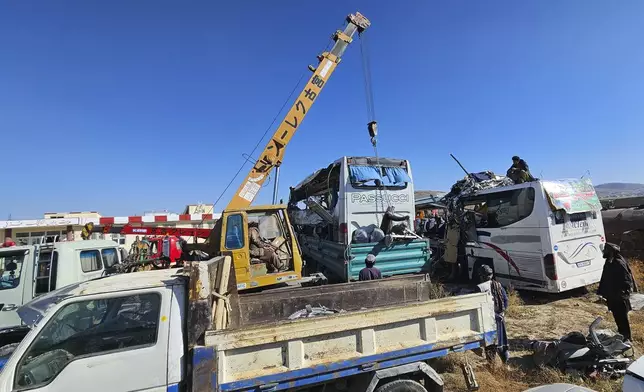 People remove damaged buses after an accident in Ghazni province, southeastern Afghanistan, Thursday, Dec. 19, 2024. (AP Photo/Gulabuddin Amiri)