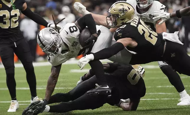 Las Vegas Raiders running back Ameer Abdullah (8) is tackled by New Orleans Saints linebacker Pete Werner (20) and safety Ugo Amadi (0) during the first half of an NFL football game, Friday, Nov. 29, 2024, in New Orleans. (AP Photo/Gerald Herbert)