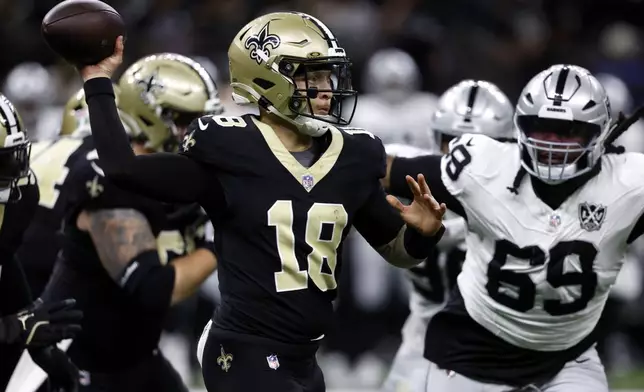 New Orleans Saints quarterback Spencer Rattler (18) throws a pass as he is pressured by Las Vegas Raiders defensive tackle Adam Butler (69) during the first half of an NFL football game, Sunday, Dec. 29, 2024, in New Orleans. (AP Photo/Butch Dill)