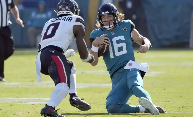 Jacksonville Jaguars quarterback Trevor Lawrence (16) slides in front of Houston Texans linebacker Azeez Al-Shaair (0) during the first half of an NFL football game Sunday, Dec. 1, 2024, in Jacksonville, Fla. Lawrence was injured on the play. (AP Photo/John Raoux)