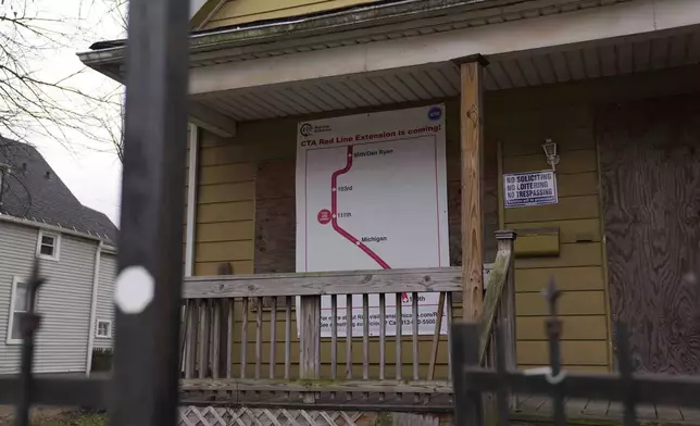 A sign reads "CTA Red Line Extension is coming!" on a boarded-up property set for demolition to make room for a new train station where the Chicago Transit Authority plans to expand the Red Line train route on West 111th Street, Wednesday, Dec. 11, 2024, in the Roseland neighborhood of Chicago. (AP Photo/Erin Hooley)