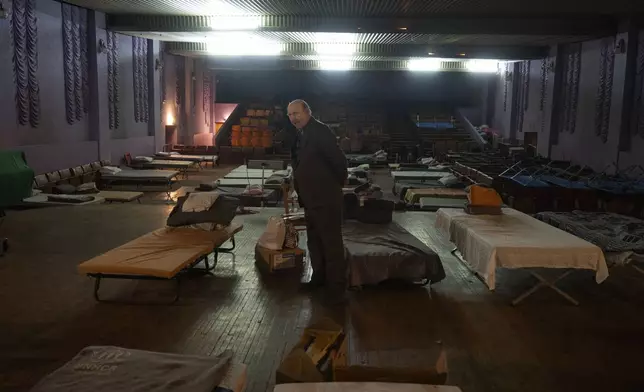 A man waits for evacuation to western Ukraine as he stands by a bed in a city theatre that hosts refugees running from Russian offensive in the Donetsk region, in Pavlohrad, Dnipropetrovsk region, Ukraine, Thursday, Dec. 12, 2024.(AP Photo/Efrem Lukatsky)