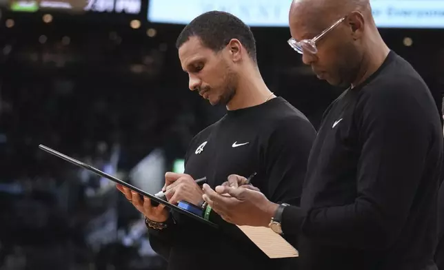 Boston Celtics head coach Joe Mazzulla, left, draws up a play as assistant coach Sam Cassell, right, takes notes during the first half of an NBA basketball game against the Miami Heat, Monday, Dec. 2, 2024, in Boston. (AP Photo/Charles Krupa)