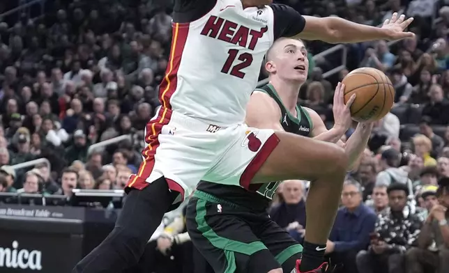 Miami Heat guard Dru Smith (12) tries to block a shot by Boston Celtics guard Payton Pritchard, right, during the first half of an NBA basketball game, Monday, Dec. 2, 2024, in Boston. (AP Photo/Charles Krupa)