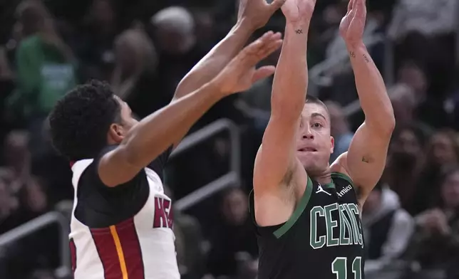 Boston Celtics guard Payton Pritchard (11) takes a 3-point shot over Miami Heat guard Dru Smith, left, during the first half of an NBA basketball game, Monday, Dec. 2, 2024, in Boston. (AP Photo/Charles Krupa)