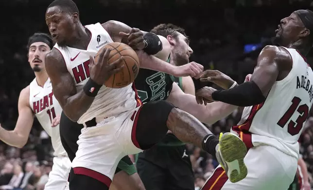 Miami Heat guard Terry Rozier, center left, battles for a rebound against Boston Celtics center Luke Kornet, center right, during the first half of an NBA basketball game, Monday, Dec. 2, 2024, in Boston. (AP Photo/Charles Krupa)