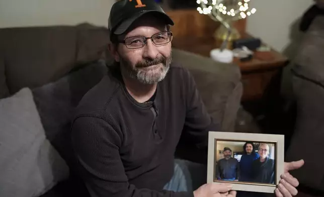 Jerry Barnett holds a picture of his wife and son on Nov. 22, 2024, in Johnson City, Tenn. Barnett's wife, Sibrina, died trying to escape flood waters caused by Hurricane Helene in September, near the plastics factory where she cleaned offices once a week. (AP Photo/George Walker IV)