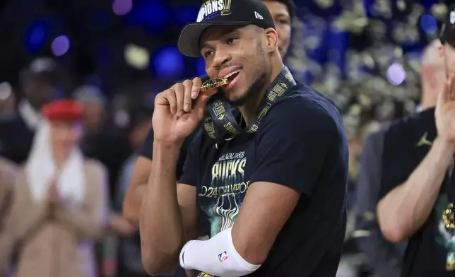 Milwaukee Bucks forward Giannis Antetokounmpo (34) bites his NBA Cup medal after his team's victory in the championship game of the NBA Cup basketball tournament against the Oklahoma City Thunder Tuesday, Dec. 17, 2024, in Las Vegas. (AP Photo/Ian Maule)