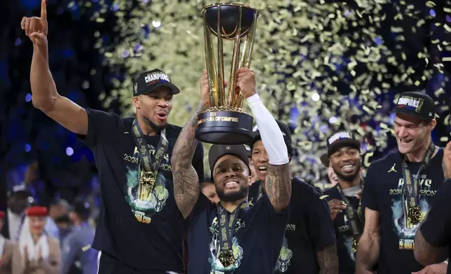 Milwaukee Bucks guard Damian Lillard (0) lifts up the NBA Cup while forward Giannis Antetokounmpo (34), left, and center Brook Lopez (11), right, celebrate after their team's victory in the championship game of the NBA Cup basketball tournament against the Oklahoma City Thunder Tuesday, Dec. 17, 2024, in Las Vegas. (AP Photo/Ian Maule)