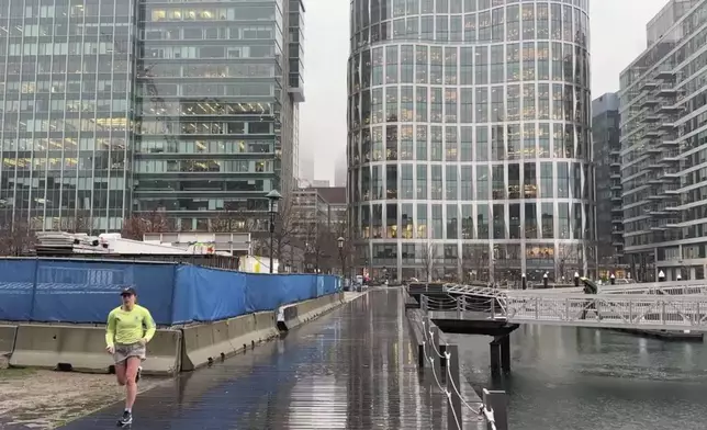 A jogger runs along the harbor as rain falls in Boston’s Seaport neighborhood on Wednesday Dec 11, 2024. (AP Photo/Michael Casey)