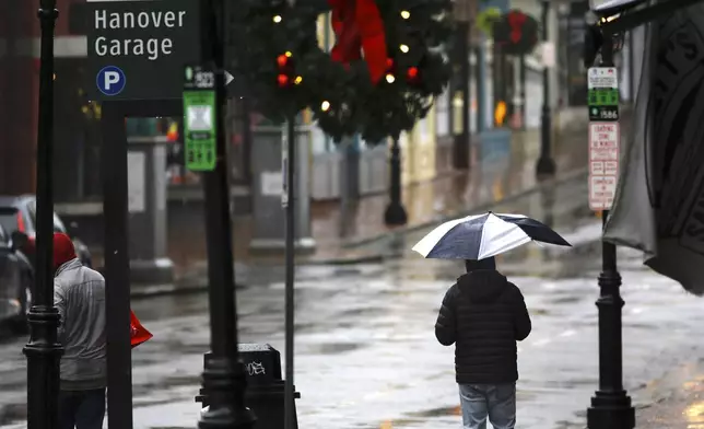 People walk through the rain as a storm system and possible "bomb cyclone" hit the U.S. East Coast, Wednesday, Dec. 11, 2024 in Portsmouth, N.H. (AP Photo/Caleb Jones)