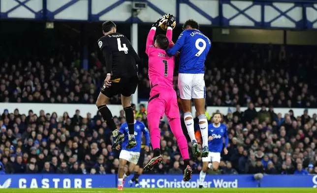 Everton's Iliman Ndiaye, not pictured, scores their side's third goal of the game before being ruled for a foul on Wolverhampton Wanderers goalkeeper Jose Sa, centre, by Dominic Calvert-Lewin, right, during the Premier League match at Goodison Park, Liverpool, Wednesday Dec. 4, 2024. (Peter Byrne/PA via AP)