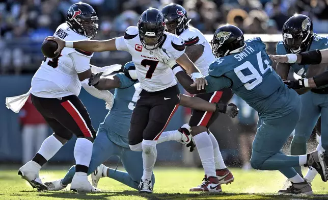 Houston Texans quarterback C.J. Stroud (7) slips a tackle by Jacksonville Jaguars defensive tackle Maason Smith (94) during the second half of an NFL football game Sunday, Dec. 1, 2024, in Jacksonville, Fla. (AP Photo/Phelan M. Ebenhack)